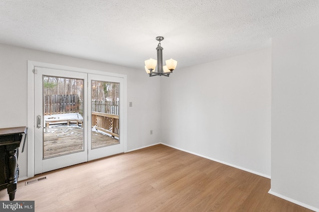 unfurnished dining area featuring a chandelier, hardwood / wood-style floors, and a textured ceiling