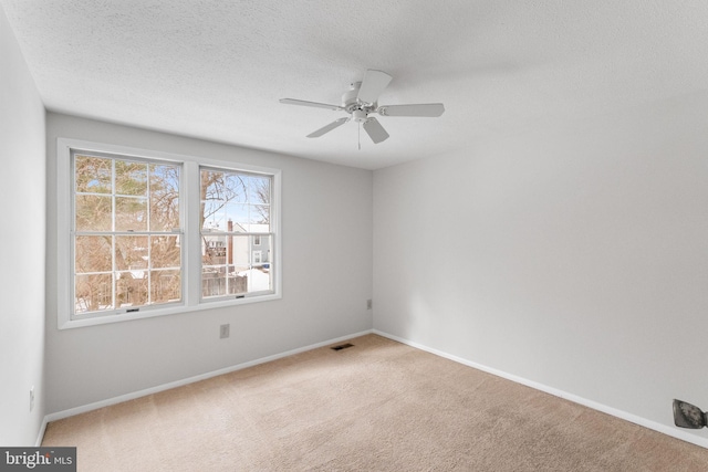 carpeted empty room with ceiling fan and a textured ceiling