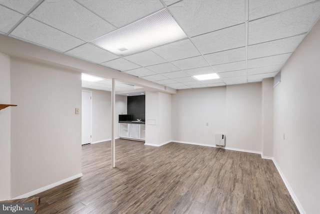 basement featuring a paneled ceiling and dark hardwood / wood-style floors