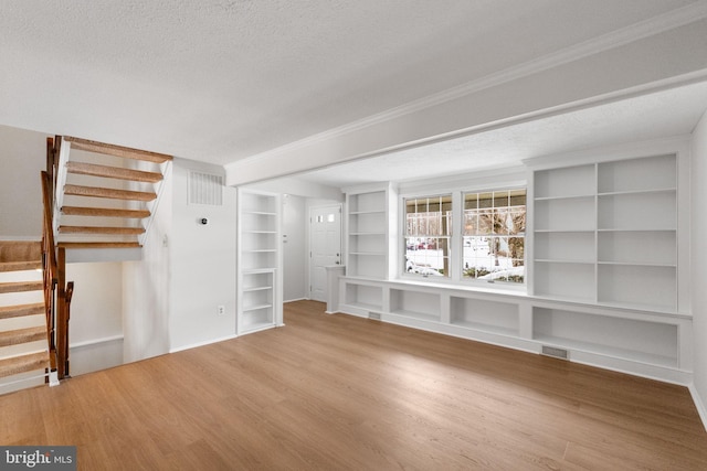 unfurnished living room featuring hardwood / wood-style floors, a textured ceiling, and built in shelves