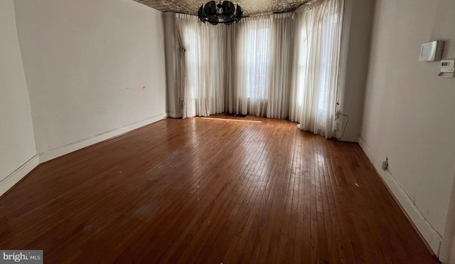 empty room featuring hardwood / wood-style floors and an inviting chandelier