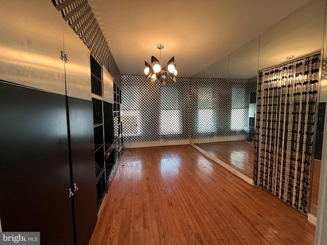 unfurnished dining area with hardwood / wood-style flooring and an inviting chandelier