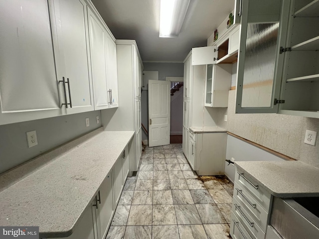 kitchen featuring light stone counters and white cabinetry