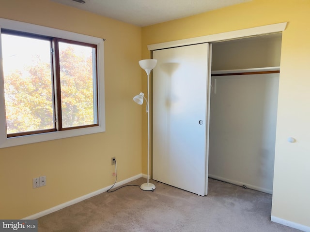 unfurnished bedroom featuring light carpet and a closet