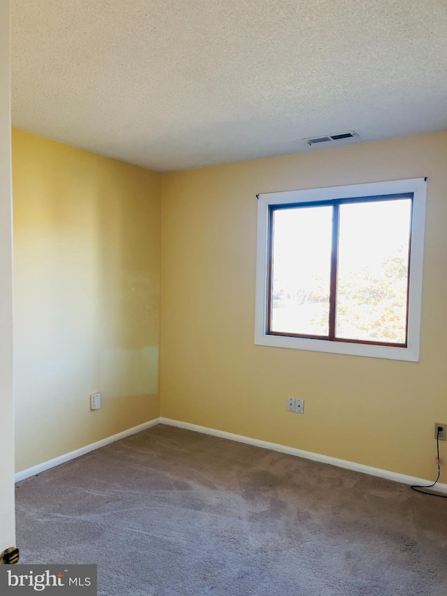 carpeted empty room with a textured ceiling