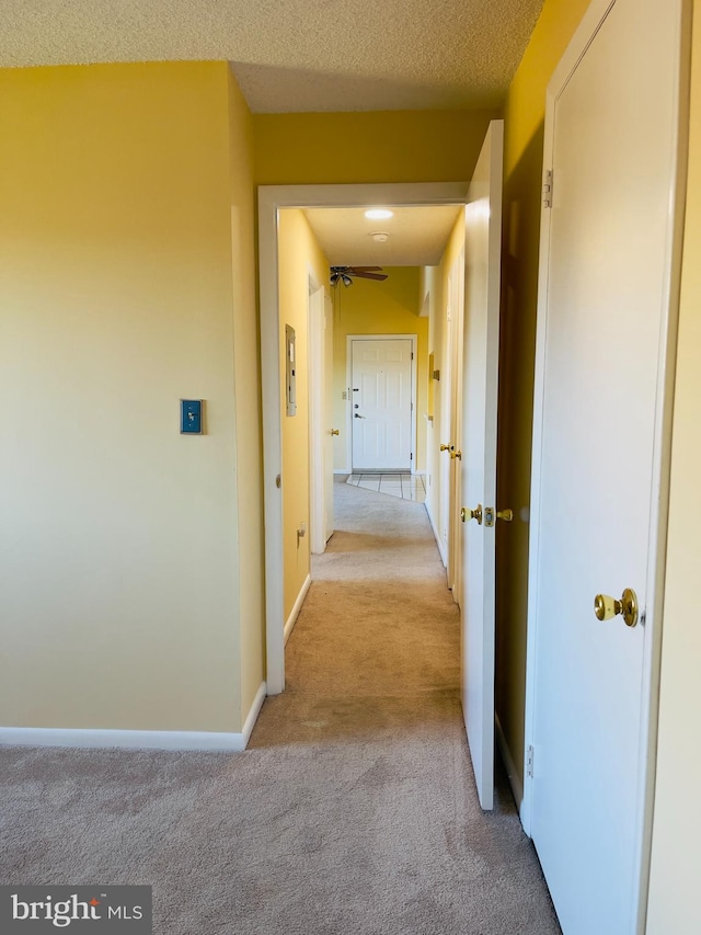 corridor featuring a textured ceiling and light carpet