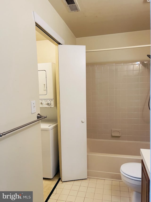 full bathroom featuring tile patterned flooring, vanity, stacked washer / drying machine, and toilet