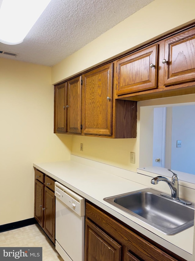 kitchen featuring white dishwasher, sink, and a textured ceiling