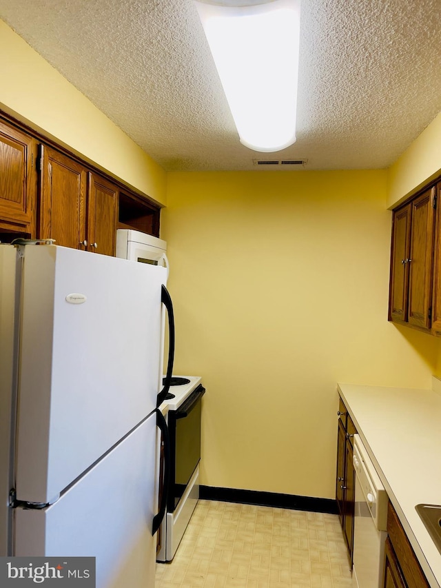 kitchen with a textured ceiling and white appliances