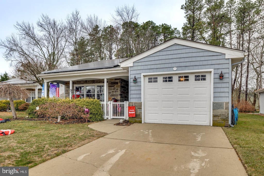 view of front facade with solar panels, a porch, a garage, and a front lawn