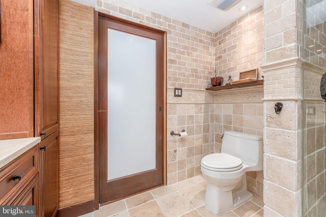 bathroom with vanity, toilet, and tile walls