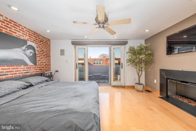 bedroom with access to outside, ceiling fan, brick wall, and hardwood / wood-style flooring