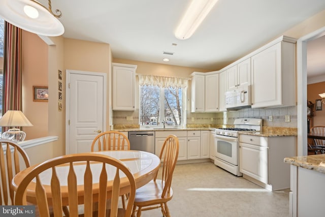 kitchen featuring white cabinets, light stone countertops, sink, and white appliances