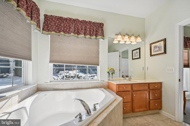 bathroom featuring tiled bath, a wealth of natural light, tile patterned flooring, and vanity