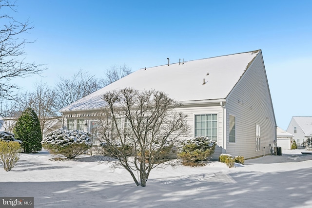 snow covered property with cooling unit and a garage