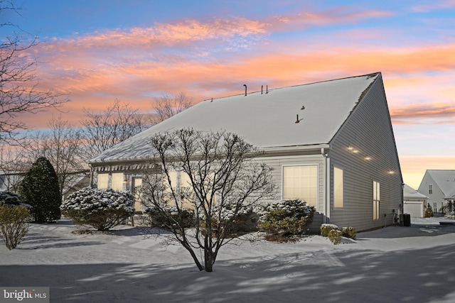 property exterior at dusk with central AC unit and a garage