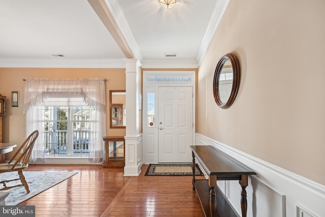 entryway with hardwood / wood-style flooring, ornamental molding, and ornate columns