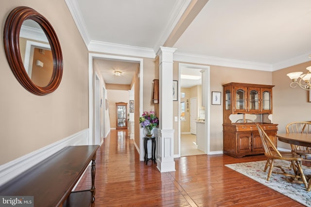 interior space with ornate columns, a chandelier, ornamental molding, and dark hardwood / wood-style floors