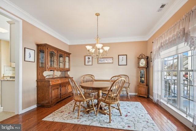 dining room with an inviting chandelier, crown molding, and hardwood / wood-style floors