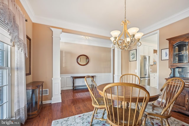 dining room with an inviting chandelier, dark hardwood / wood-style floors, crown molding, and ornate columns