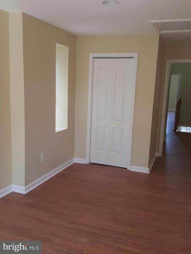 unfurnished bedroom with dark wood-type flooring and a closet