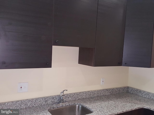 kitchen featuring light stone counters and sink