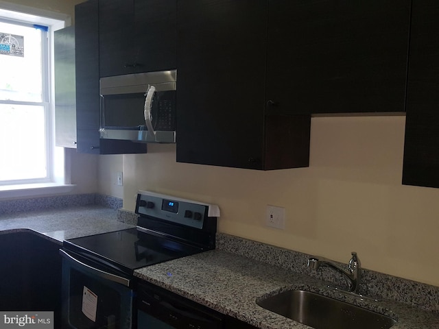 kitchen featuring light stone countertops, sink, and black appliances