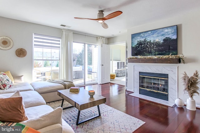 living room with a fireplace, ceiling fan, and dark wood-type flooring