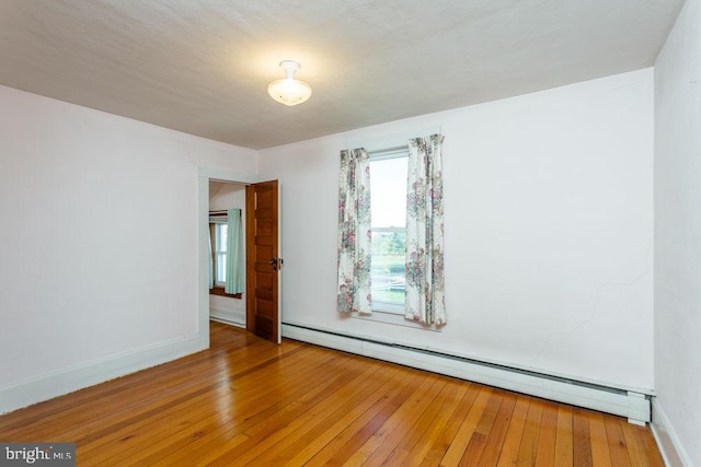 empty room with baseboard heating and hardwood / wood-style flooring