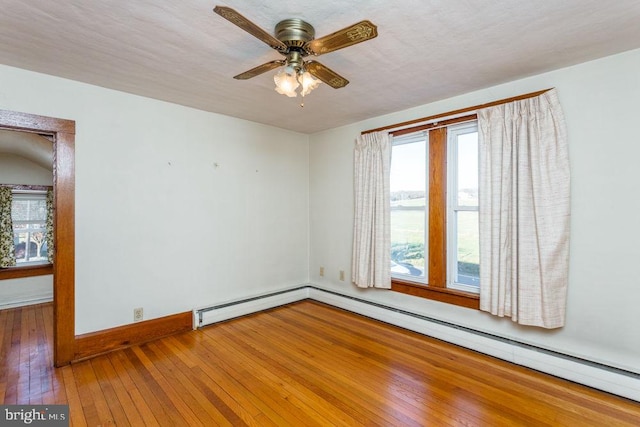 spare room with hardwood / wood-style flooring, ceiling fan, baseboard heating, and a textured ceiling