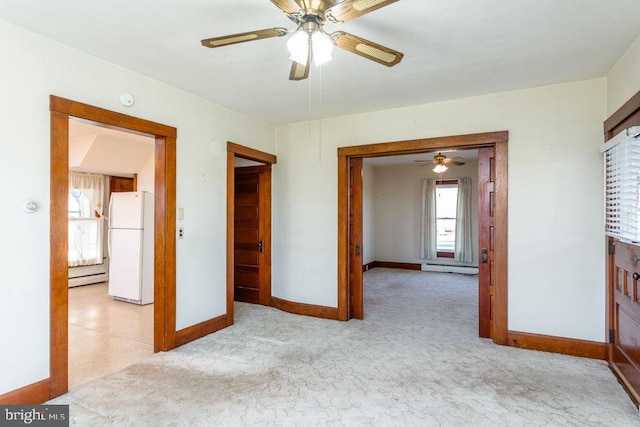 bedroom with ceiling fan, white fridge, a closet, and a baseboard heating unit