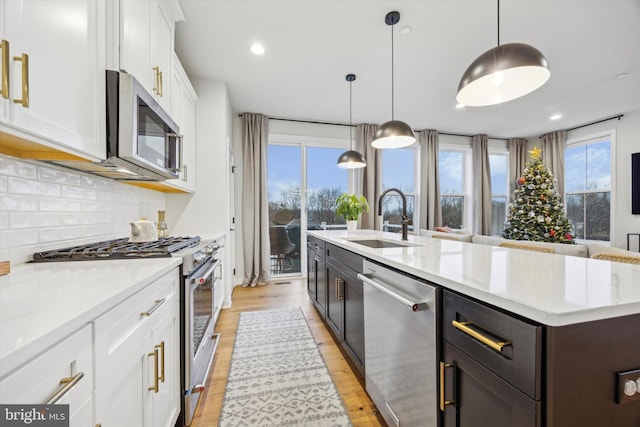 kitchen featuring pendant lighting, white cabinetry, sink, and stainless steel appliances