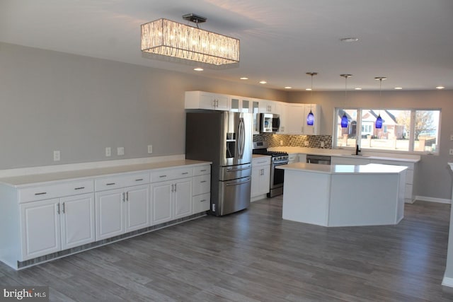 kitchen featuring decorative backsplash, appliances with stainless steel finishes, decorative light fixtures, white cabinets, and dark hardwood / wood-style floors