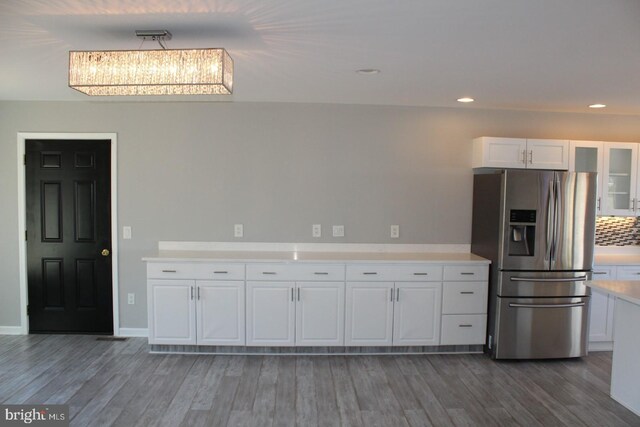 kitchen with tasteful backsplash, stainless steel fridge with ice dispenser, white cabinets, and dark wood-type flooring