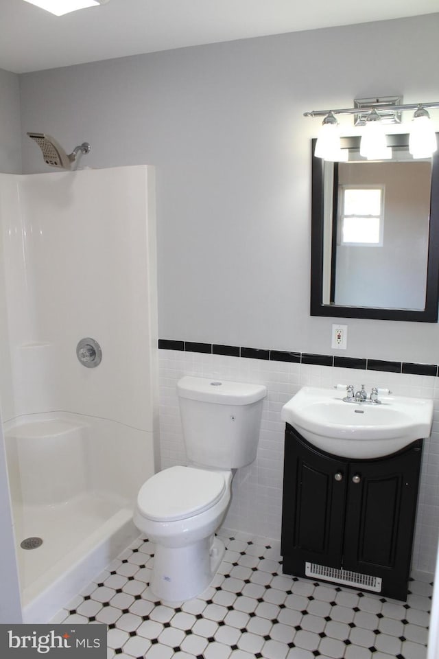 bathroom featuring walk in shower, vanity, tile walls, tile patterned flooring, and toilet