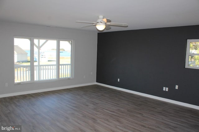 empty room featuring a wealth of natural light, dark hardwood / wood-style flooring, and ceiling fan