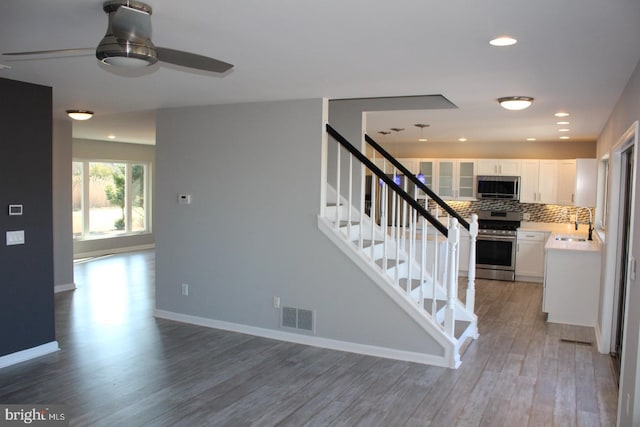 stairs featuring wood-type flooring, ceiling fan, and sink