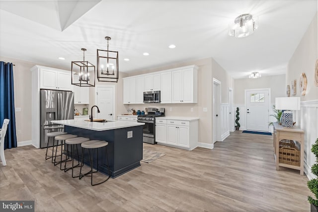 kitchen featuring stainless steel appliances, white cabinetry, and light hardwood / wood-style flooring