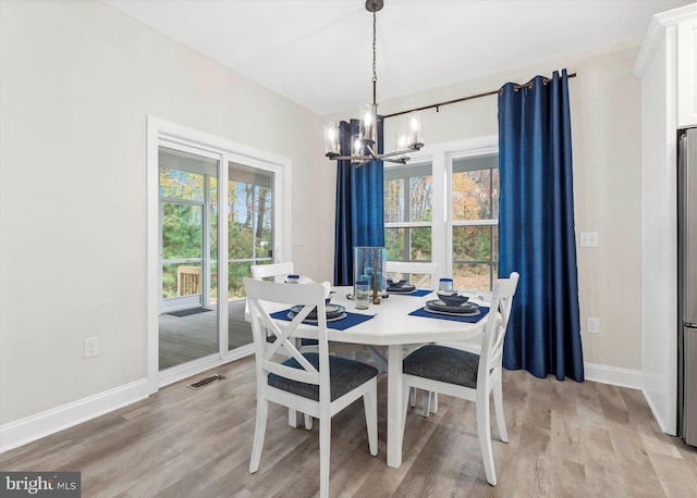 dining area with a healthy amount of sunlight, light hardwood / wood-style floors, and a chandelier