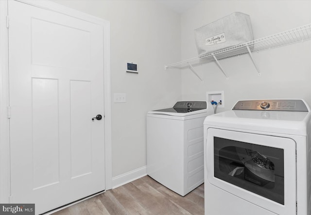 laundry room with separate washer and dryer and light hardwood / wood-style flooring