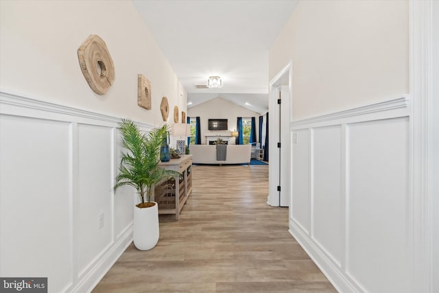 hall featuring light hardwood / wood-style flooring and lofted ceiling