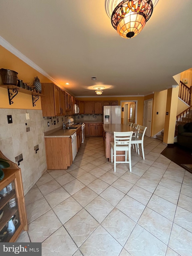 kitchen featuring a kitchen breakfast bar, ornamental molding, stainless steel appliances, sink, and a kitchen island