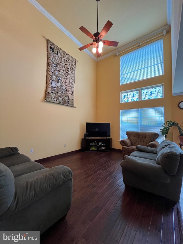 living room featuring crown molding, ceiling fan, dark wood-type flooring, and a high ceiling