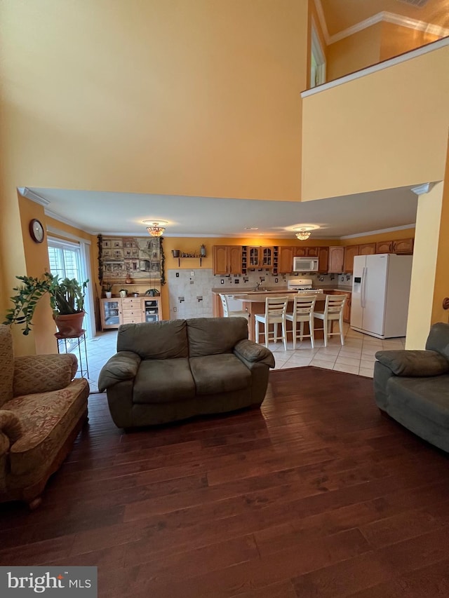 living room with a towering ceiling, light hardwood / wood-style floors, and crown molding