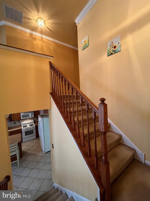 stairs featuring tile patterned floors and crown molding