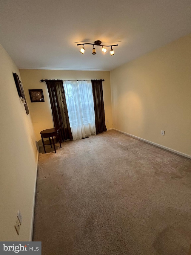 unfurnished room featuring light carpet and track lighting