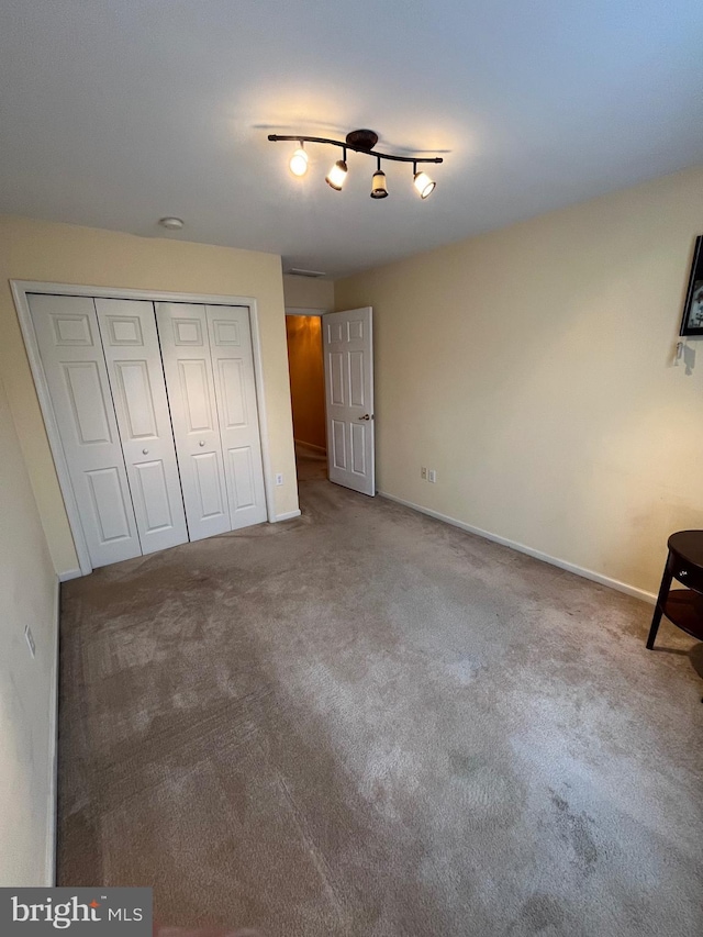 unfurnished bedroom with carpet flooring, a closet, and track lighting