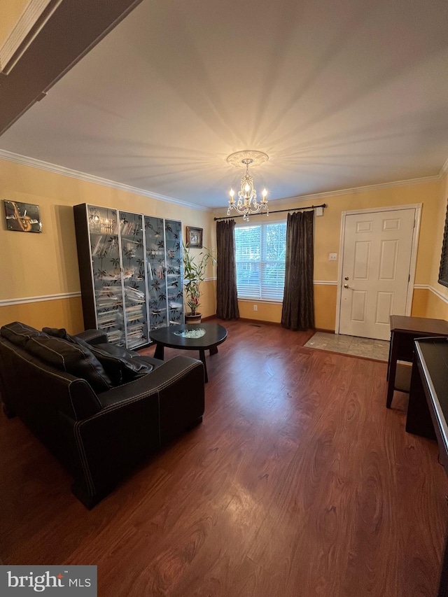 living room with crown molding, dark wood-type flooring, and an inviting chandelier