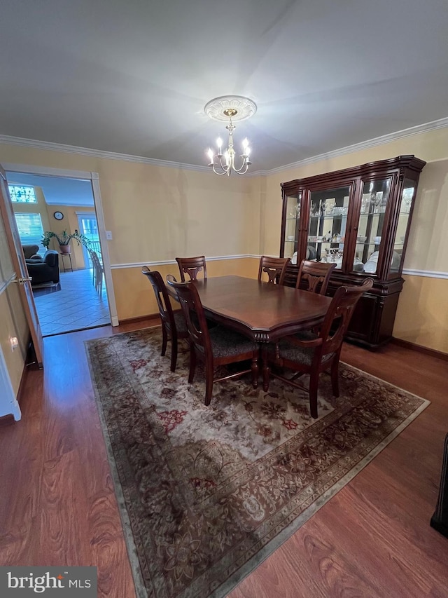 dining area with dark hardwood / wood-style flooring, ornamental molding, and an inviting chandelier