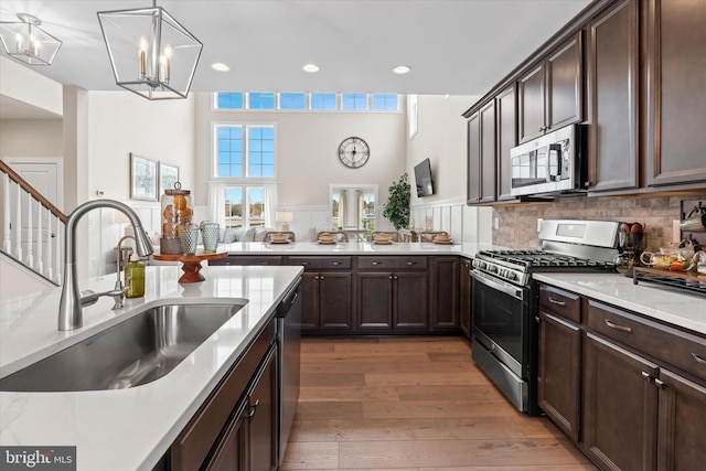 kitchen featuring appliances with stainless steel finishes, backsplash, sink, hardwood / wood-style flooring, and hanging light fixtures